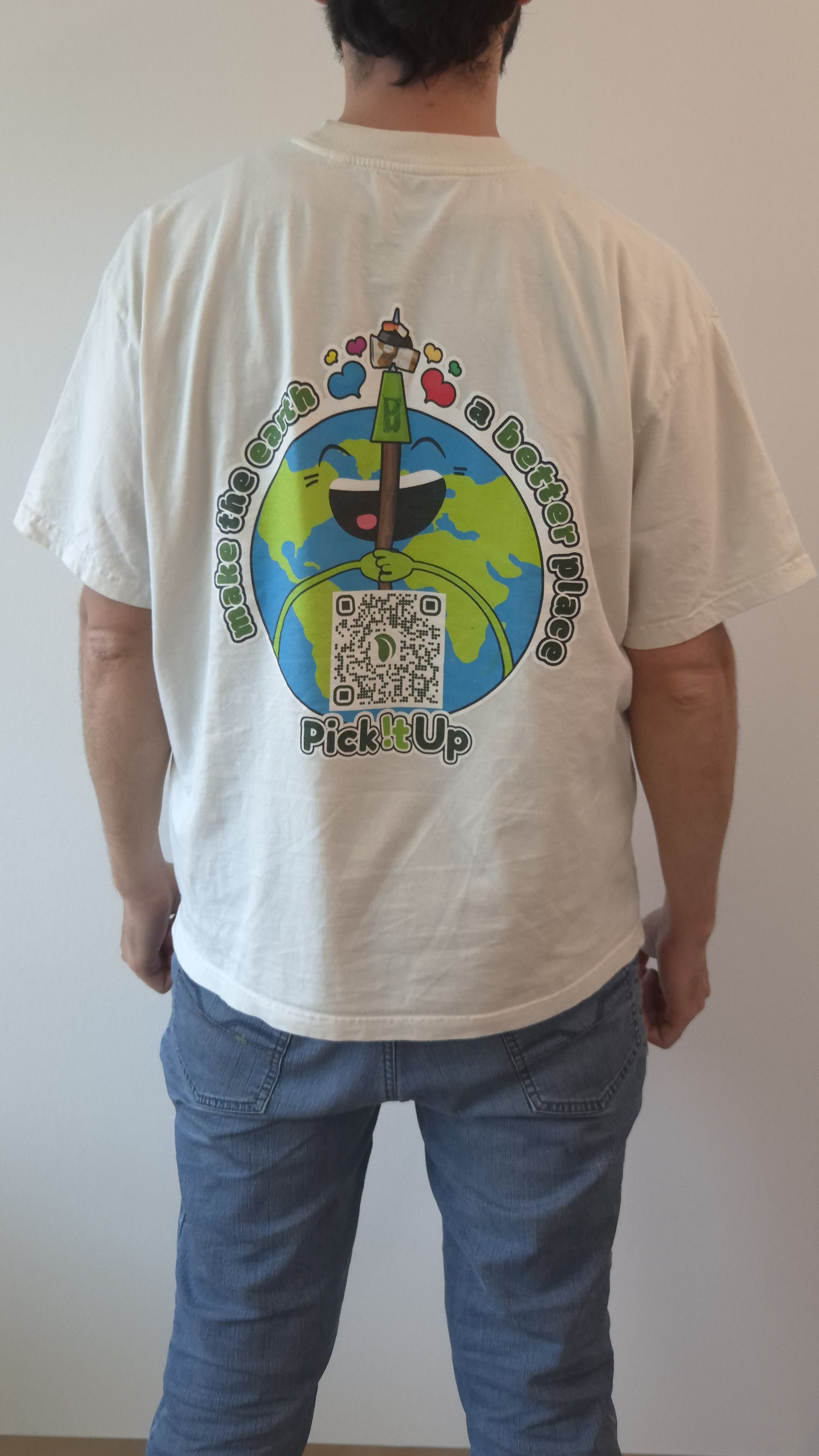 Ein T-Shirt getragen von einem Man von hinten zu sehen. Dort ist ein Aufdruck zu sehen eine Erde mit gesichtu und einem Müllpicker. drunter ist ein QR Code